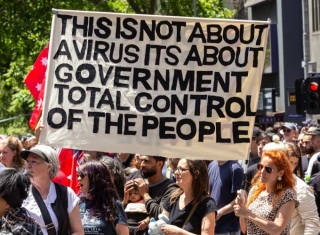 Striscione con messaggio complottista esposto durante una manifestazione